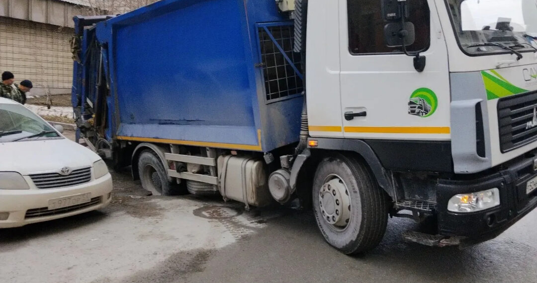 Мусоровоз провалился под асфальт в Новосибирске на улице Октябрьской